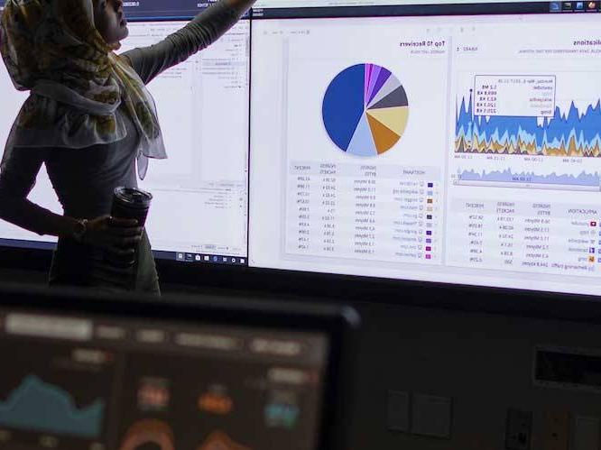 Woman infront of projector pointing to colorful graphs on the screen